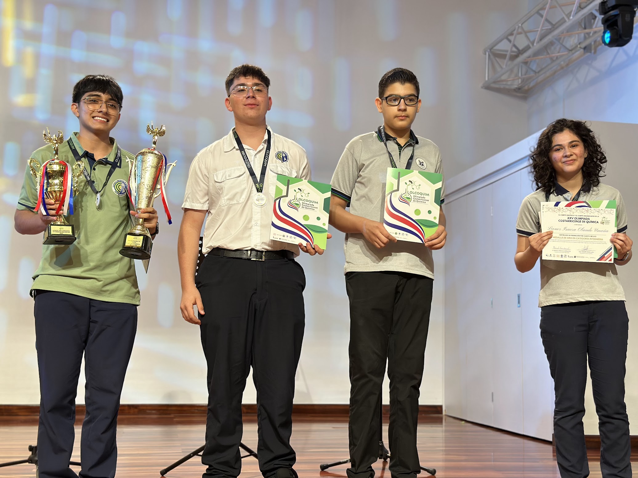 4 jóvenes ganadores sosteniendo su título y medalla