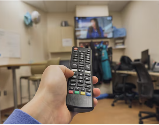 mano humana con control renoto cambiando canal de TV